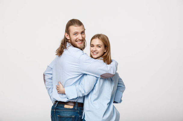 Портрет веселой молодой пары, стоящей и обнимающей друг друга на изолированном белом фоне
 - Фото, изображение