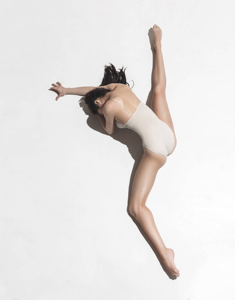 Young beautiful dancer in beige dress dancing on gray background - Fotografie, Obrázek