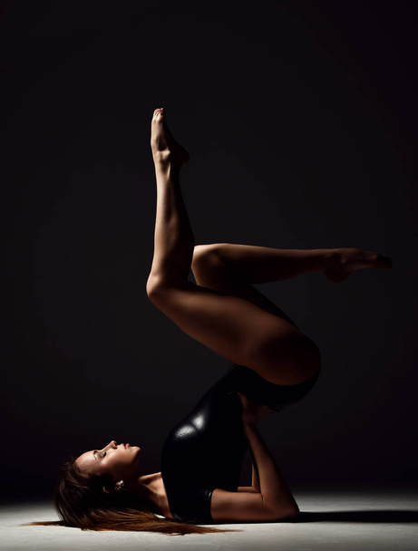 Young sport woman gymnastics doing stretching fitness exercise at dark gym  - Valokuva, kuva