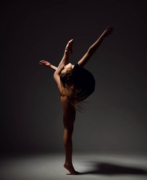 Young sport woman gymnastics doing stretching fitness exercise at dark gym  - Φωτογραφία, εικόνα