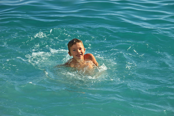 Έφηβος αγόρι κολύμβησης σε τη θάλασσα ή τον ωκεανό ζεστή ηλιόλουστη μέρα - Φωτογραφία, εικόνα
