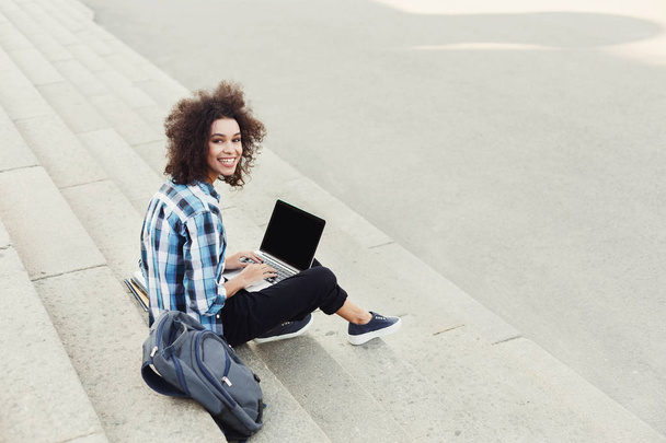 Heureuse jeune femme utilisant un ordinateur portable à l'extérieur
 - Photo, image