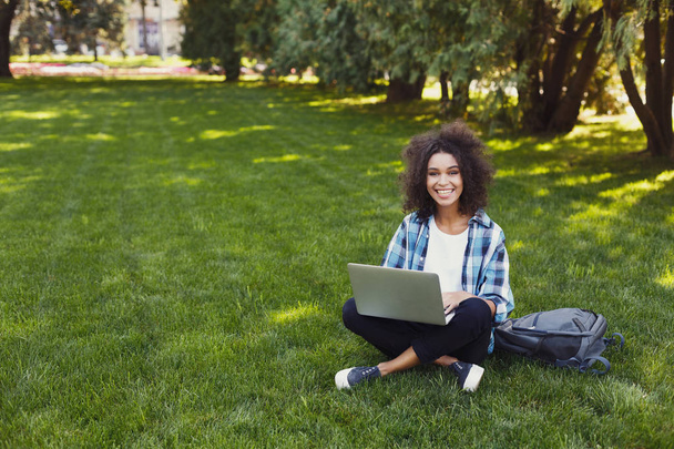 Jovencita alegre usando laptop en el parque
 - Foto, imagen