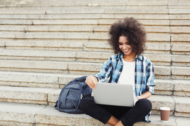 Estudante sorrindo sentado nas escadas usando laptop
 - Foto, Imagem