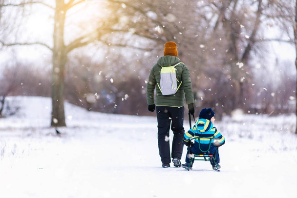 Père et fils avec un traîneau dehors dans la neige
 - Photo, image