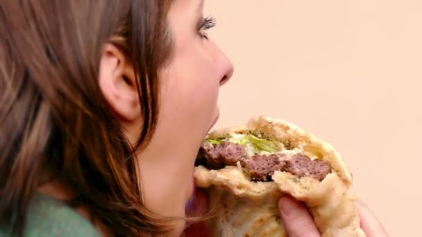 Jonge vrouw is het eten van een sappige hamburger met varkensvlees en groene salade, 4k Video Clip - Video