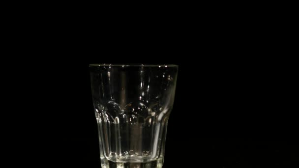 Pouring milk in long stream into a glass on black background - Filmagem, Vídeo