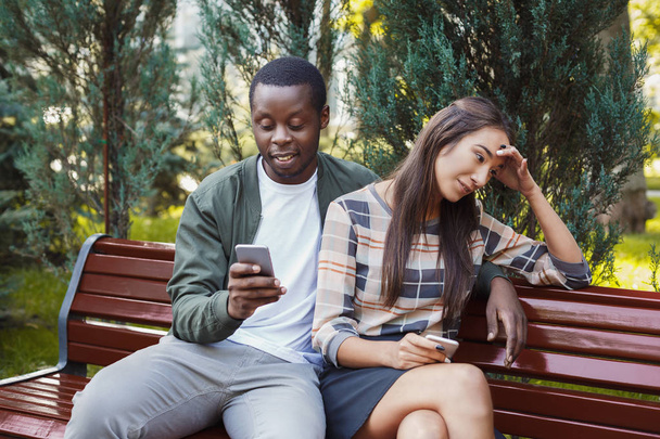Donna seduta nel parco con l'uomo utilizzando lo smartphone
 - Foto, immagini