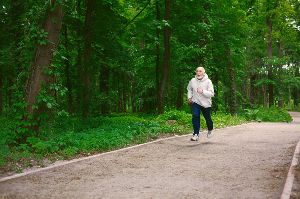 Літній чоловік біжить у зеленому лісі, копіювати простір
 - Фото, зображення
