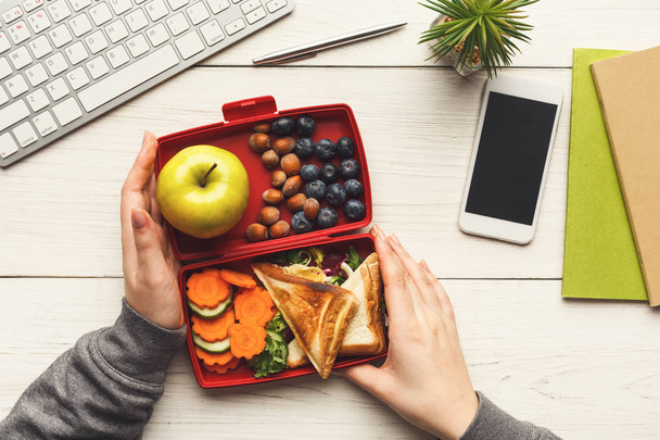 Kobieta jedzenie zdrowe Kanapki z lunch box przy jej stole roboczym - Zdjęcie, obraz