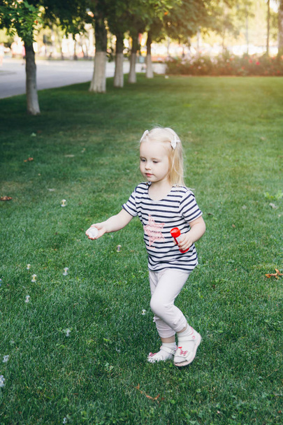Little girl inflate soap bubbles on the lawn - Foto, immagini