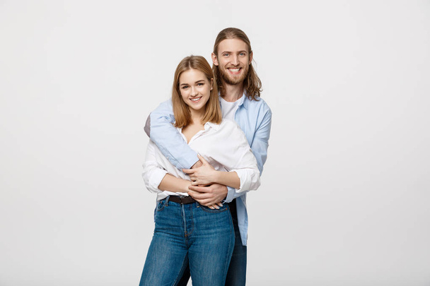 Portrait of cheerful young couple standing and hugging each other on isolated white background - Foto, Imagen