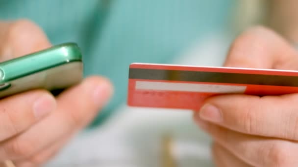 Un hombre compra bienes en una tienda en línea y paga una tarjeta de crédito a través de su teléfono
 - Imágenes, Vídeo