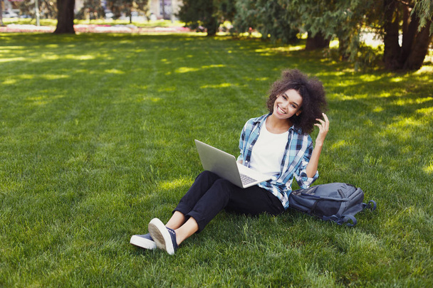Cheerful young woman using laptop in park - Photo, image