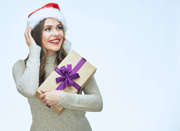 Beautiful surprised woman wearing Santa hat holding gift box  - 写真・画像