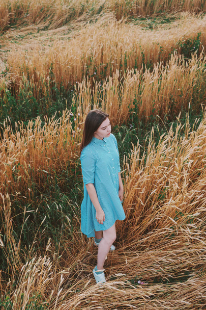 A girl is standing in a field of wheat. - Foto, Imagen