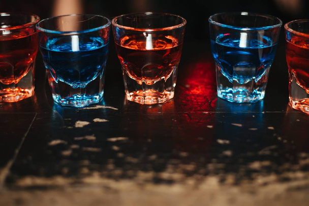 Αλκοόλ μπαρ, ποτήρι κοκτέιλ στο μπαρ γυαλί counter, κοκτέιλ στο μπαρ, πόσιμο κοκτέιλ στο μπαρ, κοκτέιλ στο γυαλί με καλαμάκια, φρέσκο ποτό κοκτέιλ σε ένα χρώμα φόντου - Φωτογραφία, εικόνα