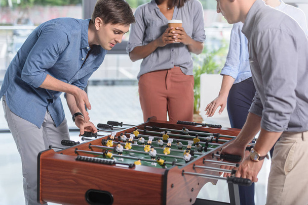 Young businessmen playing table football in modern office - Foto, afbeelding