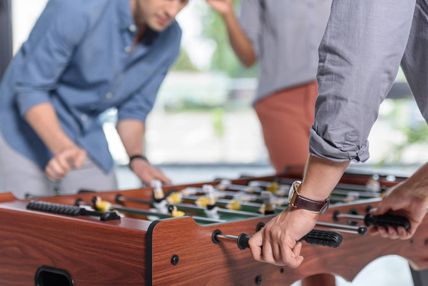 Businessmen playing table football in modern office - Foto, afbeelding