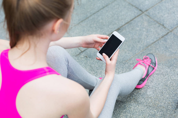 Sporty woman holding smartphone with copy space - Photo, Image