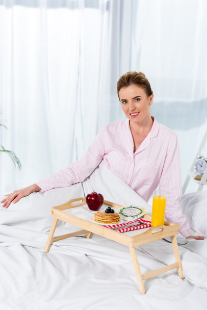 happy woman in pajamas with breakfast in bed - Foto, Imagen