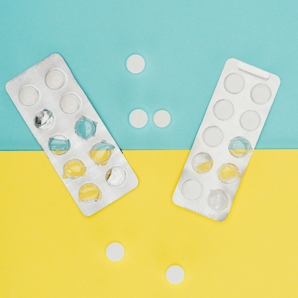 Κάτοψη των φαρμάκων που απομονώνονται σε μπλε και κίτρινο φόντο - Φωτογραφία, εικόνα