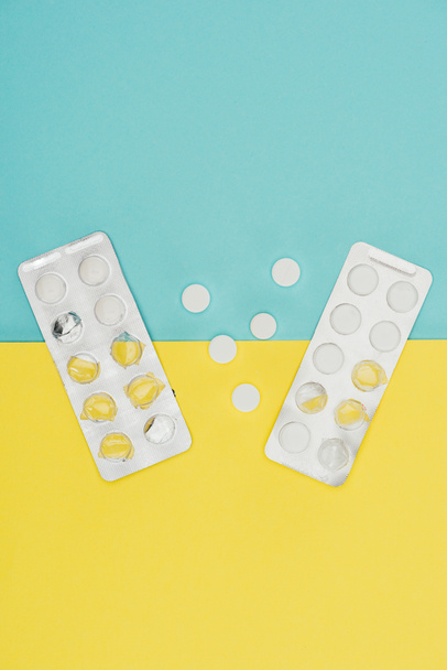 vista superior de los medicamentos aislados sobre fondo azul y amarillo
 - Foto, Imagen