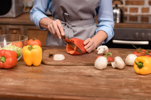 cropped image of woman cutting red bell pepper on wooden board  - Photo, Image