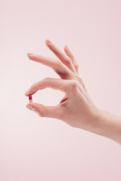 partial view of woman holding medicine in hand isolated on pink - Foto, afbeelding