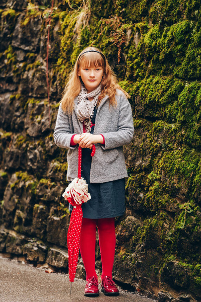 Наружный портрет красивой 9-10-летней девочки в сером пальто и шарфе, с красным зонтиком в горошек.
 - Фото, изображение