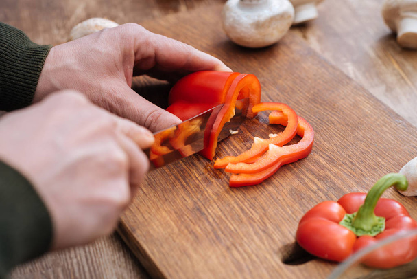 cropped image of man cutting bell pepper in kitchen - Fotografie, Obrázek