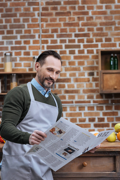 handsome man reading travel newspaper in kitchen - Foto, imagen
