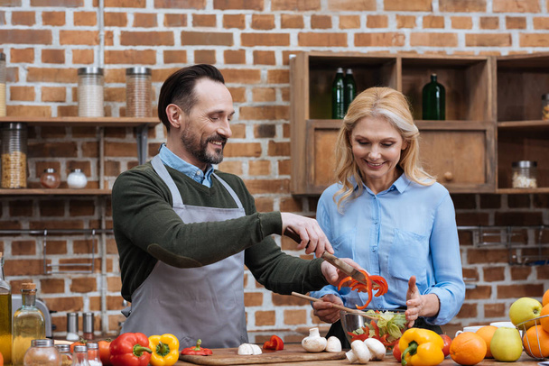 happy couple preparing salad in kitchen - Фото, изображение