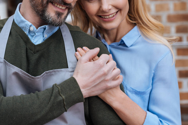 abgeschnittenes Bild eines lächelnden Ehepaares beim Händchenhalten - Foto, Bild
