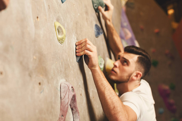 Молодий чоловік піднімається на штучну кам'яну стіну в спортзалі
 - Фото, зображення