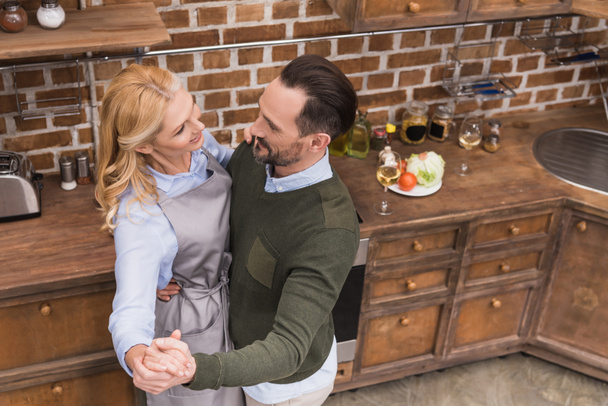 vista aérea de sonriente esposa y marido bailando en la cocina
 - Foto, imagen