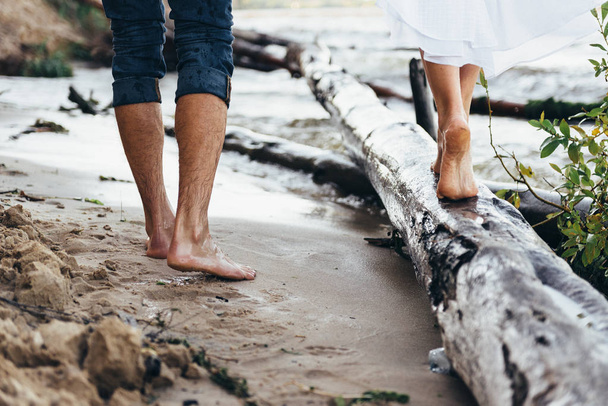 legs of a guy and a girl walking along the beach, the girl is st - Φωτογραφία, εικόνα