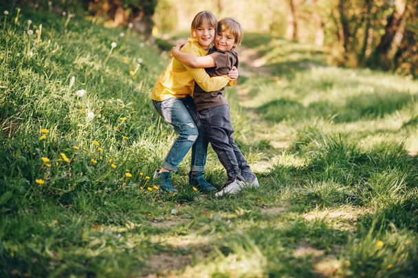 Dwie śmieszne dzieci grając razem w lesie wiosną, mały brat i siostra, ciesząc się miły spacer w lesie - Zdjęcie, obraz