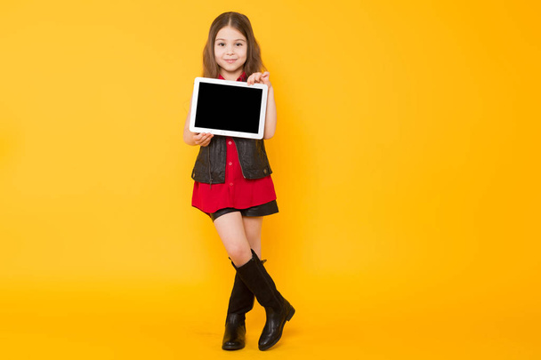 Carino piccola ragazza bruna che tiene tablet digitale su sfondo giallo studio
  - Foto, immagini