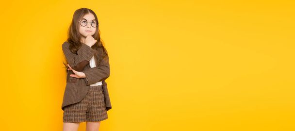 Ajattelevainen söpö pieni tyttö poseeraa keltaista taustaa vasten
  - Valokuva, kuva