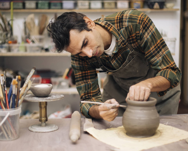 Jonge man maken van aardewerk in werkplaats - Foto, afbeelding