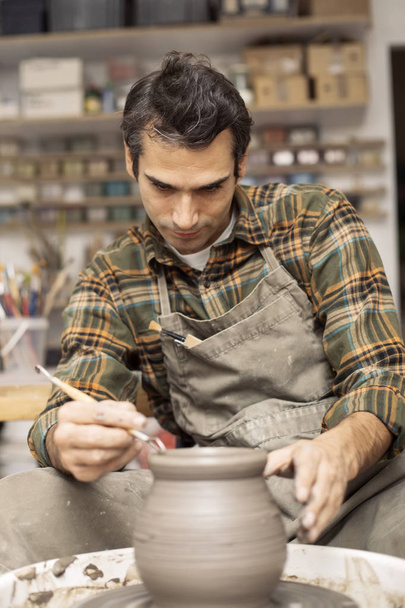 Artista hace cerámica de arcilla en una rueda giratoria
 - Foto, Imagen