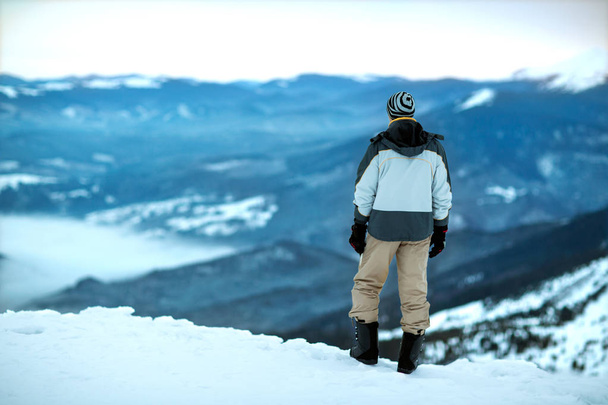 the guy is standing on top of a snowy mountain looking into the  - Foto, Imagen