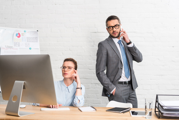 businessman talking by phone while his colleague trying to work with computer - Photo, image