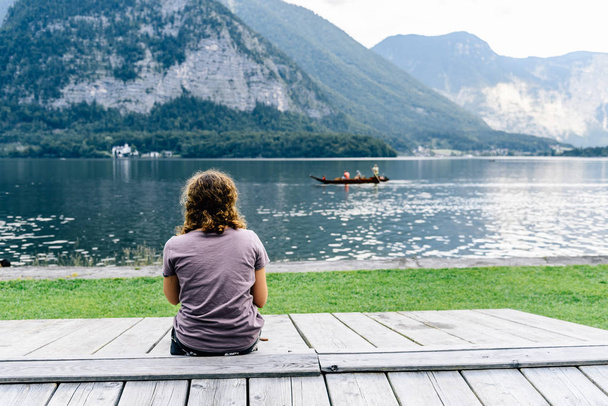 Жінка сидить на пірсі на березі озера
 - Фото, зображення