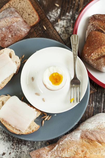 oeuf cuit sur une assiette, pain fraîchement cuit et sandwichs au bacon sur une table en bois
 - Photo, image