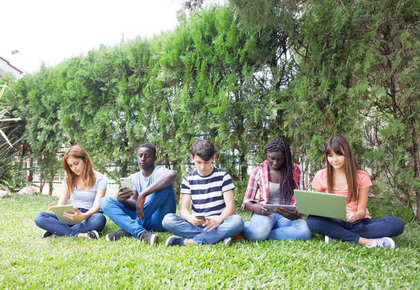 Adolescentes al aire libre usando computadora portátil y tableta y teléfono inteligente
. - Foto, imagen