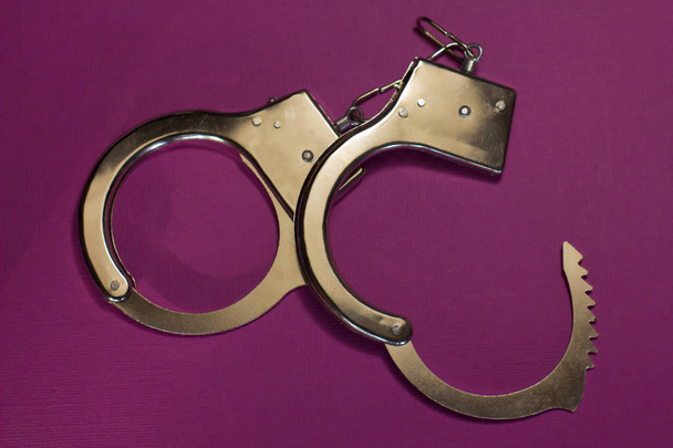 Handcuffs on crimson background - Foto, Imagen