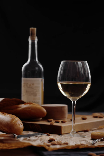 A glass of white wine on a table on a dark background.  - Foto, immagini