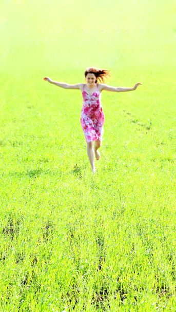 Focus on green grass. Blurred front view young woman in red dres - Foto, immagini